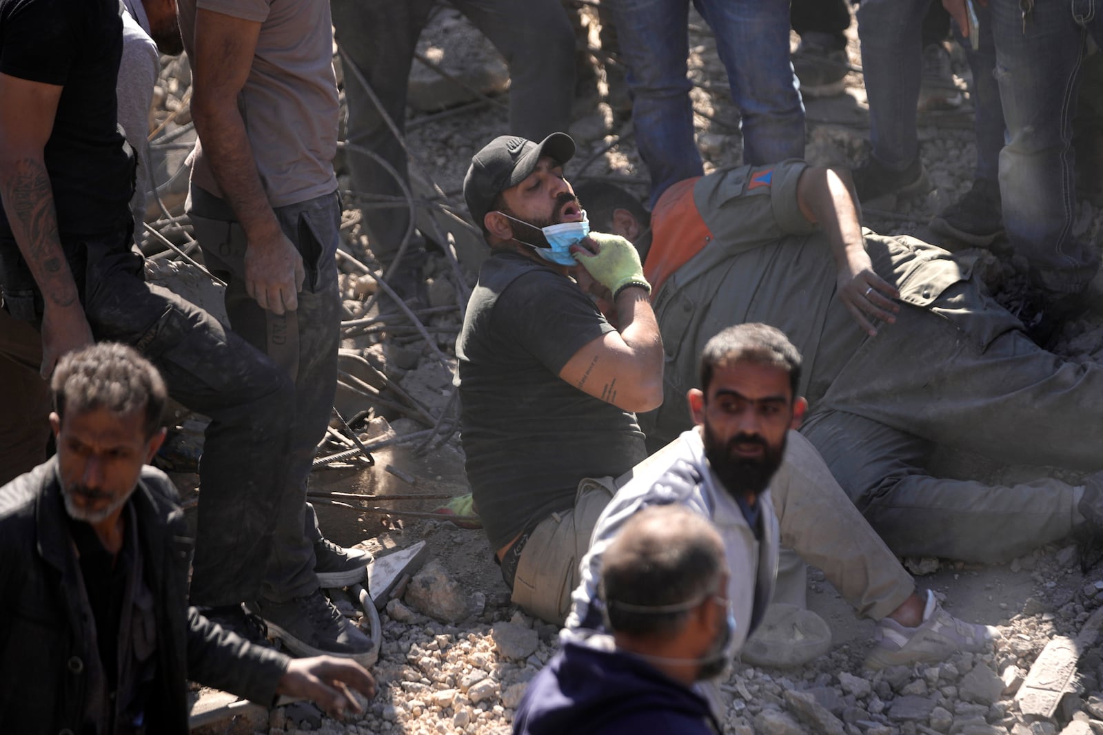 A rescue worker, center, takes off his mask to breathe, as he works at the site of Israeli airstrikes that destroyed buildings facing the city's main government hospital in southern Beirut, Lebanon, Tuesday, Oct. 22, 2024. (AP Photo/Hussein Malla)