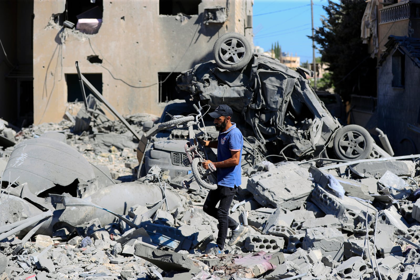 A man carries a damaged bicycle at the site of an Israeli airstrike in Saksakieh, south Lebanon, Thursday, Sept. 26, 2024. (AP Photo/Mohammed Zaatari)