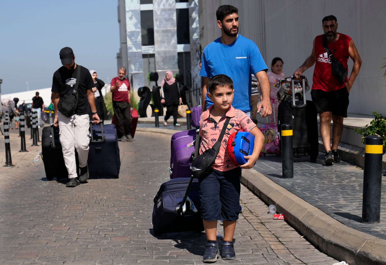 Turkish citizens carry their belongings, as they arrive at a gathering point to board a Turkish navy vessel to be evacuated to Turkey, in Beirut, Lebanon, Wednesday, Oct. 9, 2024. (AP Photo/Hussein Malla)