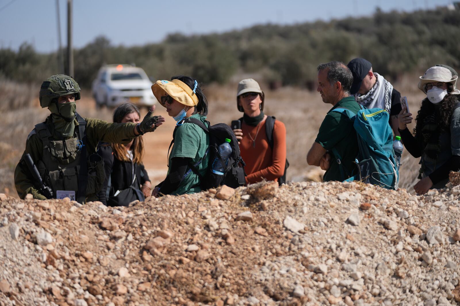 Israeli army troops check the identification documents of foreign activists and three European politicians, who joined the villagers on occasion of the Palestinian olive harvest season, and denied farmers access to their land in the West Bank town of Qusra, south of Nablus Tuesday, Oct. 29, 2024. (AP Photo/Nasser Nasser)