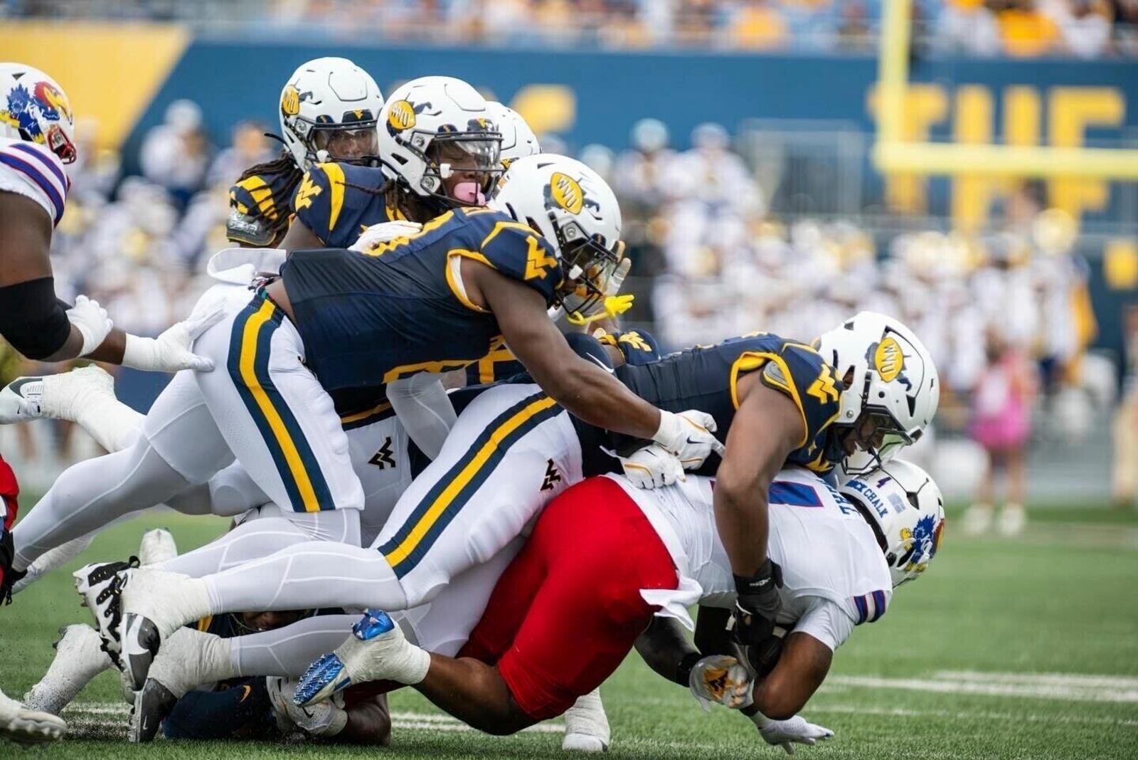 West Virginia defenders tackle Kansas running back Devin Neal, right, during an NCAA college football game Saturday, Sept. 21, 2024, in Morgantown, W.Va. (Benjamin Powell/The Dominion-Post via AP)