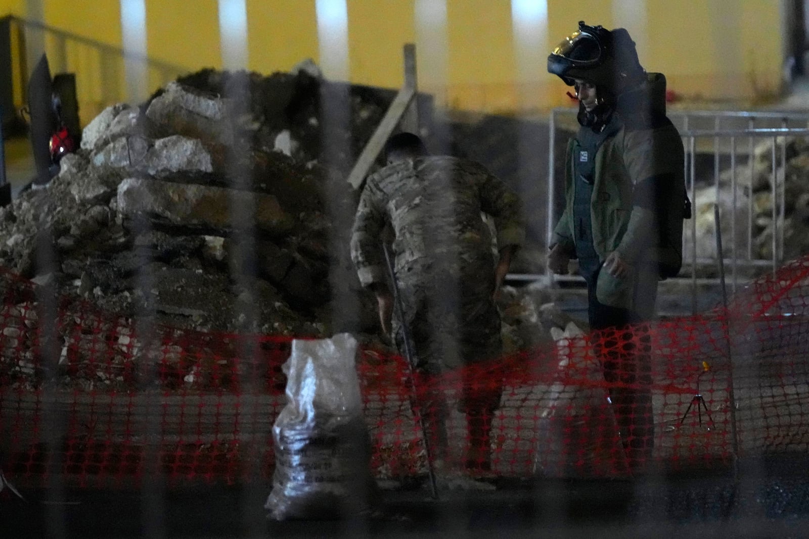 A Lebanese army bomb disposal specialist wearing a protective gear prepares, with his comrade, to detonate a walkie-talkie that was found at the parking of the American University Hospital, in Beirut, Lebanon, Wednesday, Sept. 18, 2024. (AP Photo/Hassan Ammar)