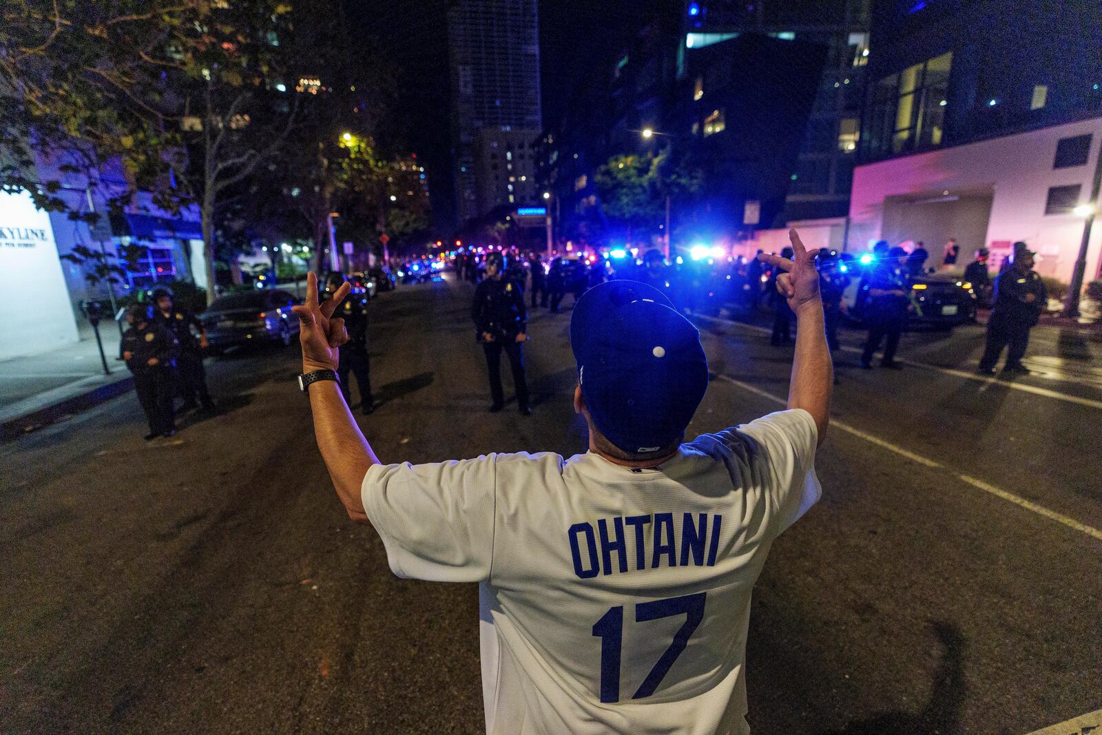 A fan wearing a Shohei Ohtani taunts Los Angeles Police officers as fans celebrate on the streets after the Los Angeles Dodgers won against the New York Yankees in the baseball World Series Wednesday, Oct. 30, 2024, in downtown Los Angeles. (AP Photo/Damian Dovarganes)