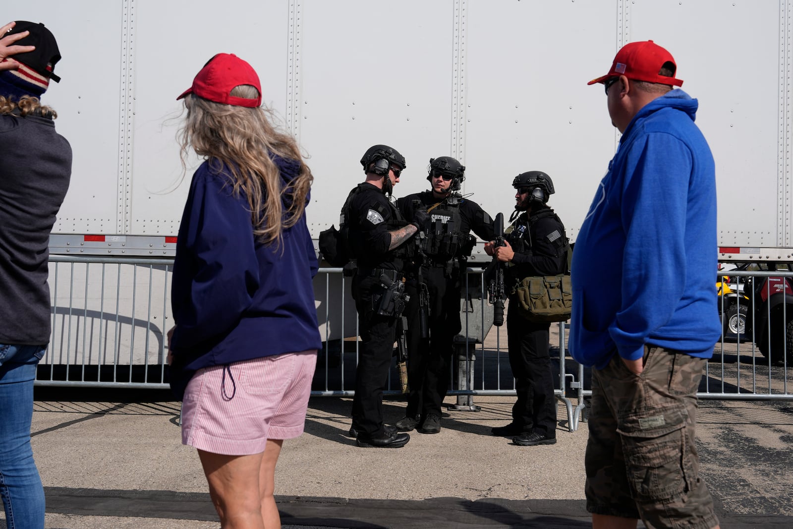 Members of law enforcement talk as people wait for Republican presidential nominee former President Donald Trump to speak during a campaign rally at Dodge County Airport, Sunday, Oct. 6, 2024, in Juneau, Wis. (AP Photo/Julia Demaree Nikhinson)