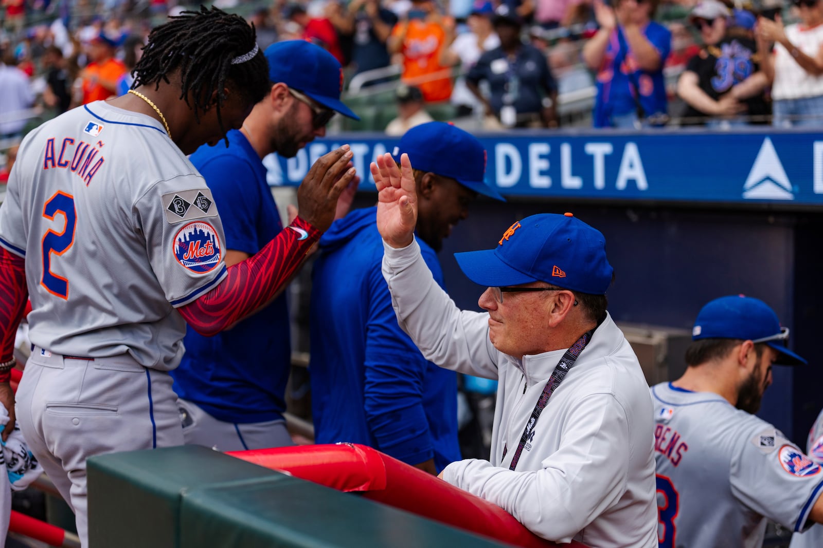 New York Mets owner, Steve Cohen, right, high fives Luisangel Acuña in the dugout after winning the game in the ninth inning of a baseball game against the Atlanta Braves, Monday, Sept. 30, 2024, in Atlanta. (AP Photo/Jason Allen)