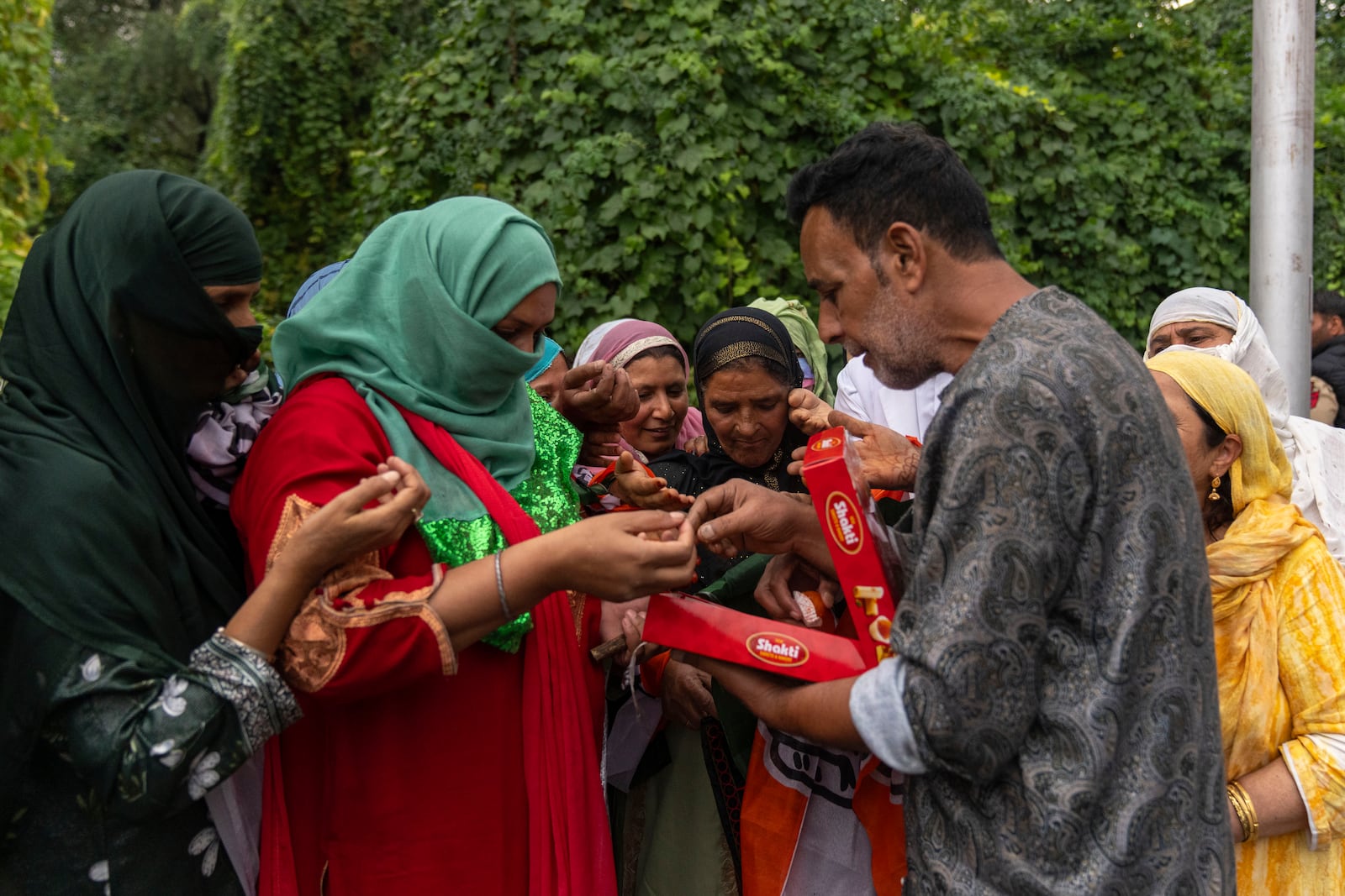 Kashmiri man distributes sweets among supporters of Indian National Congress and National Conference party as they celebrate early leads in the election for a local government in Indian controlled Kashmir, Srinagar, Tuesday, Oct. 8, 2024. (AP Photo/Dar Yasin)