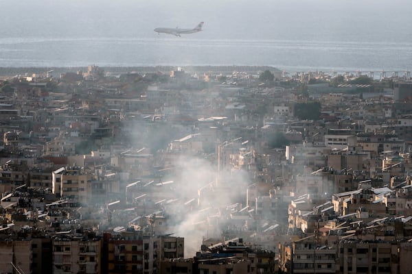 A Middle East Airlines airplane flies over Dahiyeh as smoke rises from Israeli an airstrike, in the southern suburb of Beirut, Lebanon, Saturday, Nov. 16, 2024. (AP Photo/Bilal Hussein)