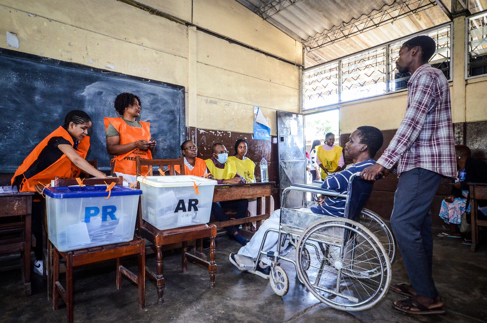 A woman in a wheelchair is helped at a polling station to vote in general elections in Maputo, Mozambique, Wednesday, Oct. 9, 2024. (AP Photo/Carlos Equeio)