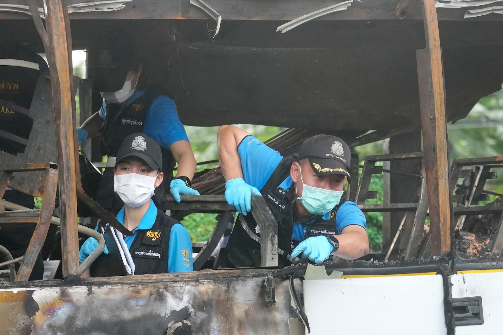 Officers of a police forensics team inspect a bus that caught fire, carrying young students with their teachers, in suburban Bangkok, Tuesday, Oct. 1, 2024. (AP Photo/Sakchai Lalit)