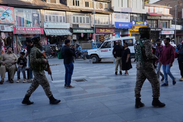 Indian paramilitary soldiers patrol as tourists take pictures at a busy market in Srinagar, Indian controlled Kashmir, Tuesday, April 29, 2025. (AP Photo/Mukhtar Khan)