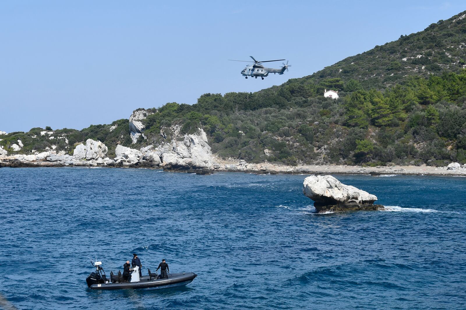 A helicopter and a vessel with coast guards officers take part in a search and rescue operation after a boat carrying migrants ran into trouble off the coast of the eastern Aegean Sea island of Samos, Greece, on Monday, Sept. 23, 2024. (AP Photo/Michael Svarnias)