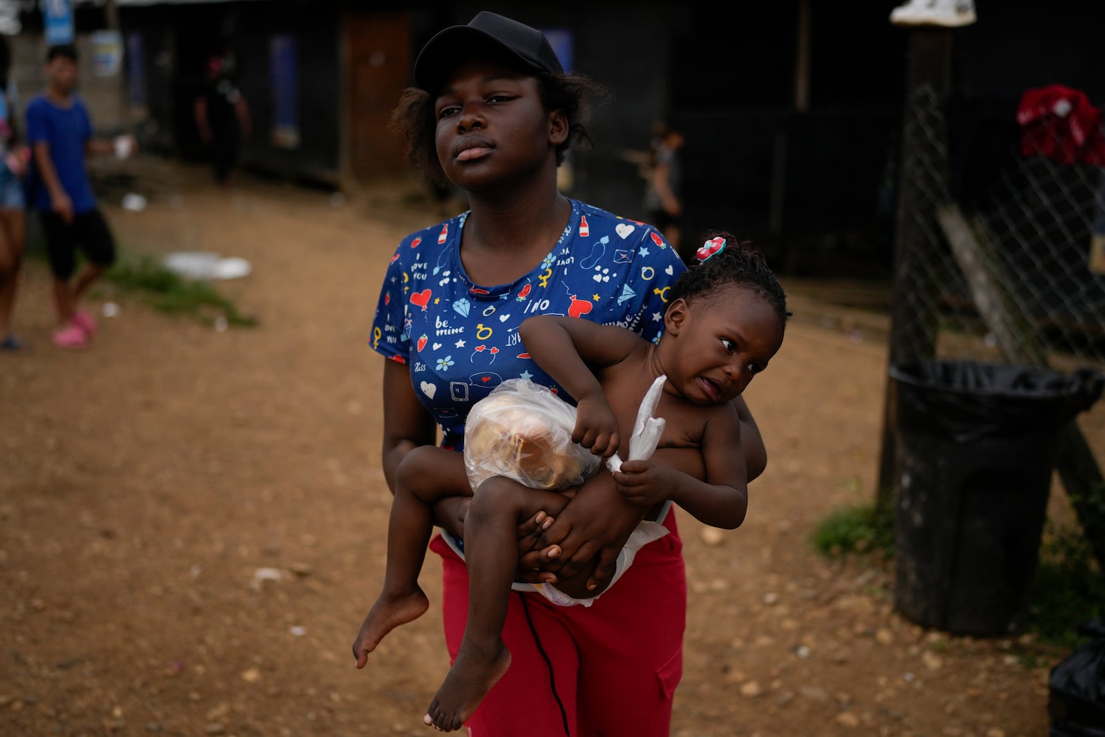 Dorcas Many, from Democratic Republic of the Congo, carries her daughter Maria Many at a camp where migrants who walked across the Darien Gap stop in Lajas Blancas, Panama, Thursday, Sept. 26, 2024. (AP Photo/Matias Delacroix)