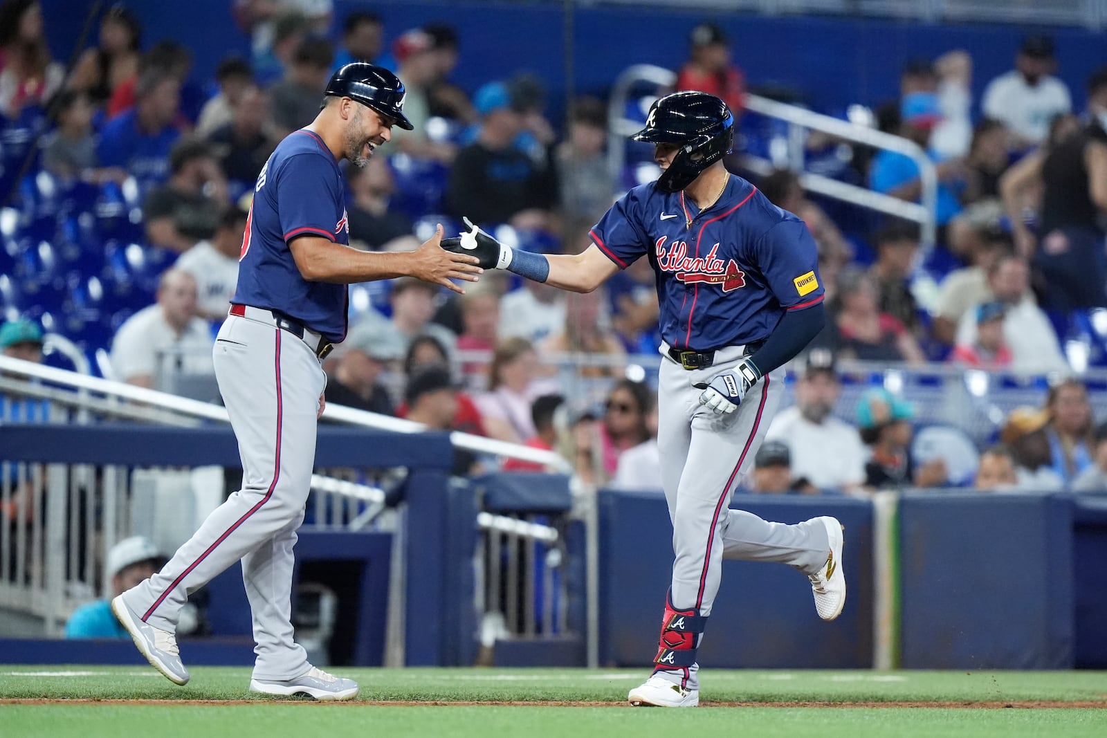 Atlanta Braves' Gio Urshela, right, is congratulated by third base coach Matt Tuiasosopo after Urshela hit a home run during the sixth inning of a baseball game against the Miami Marlins, Sunday, Sept. 22, 2024, in Miami. (AP Photo/Wilfredo Lee)