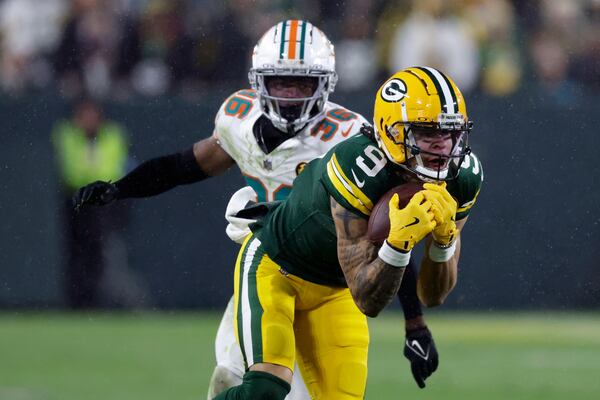 Green Bay Packers wide receiver Christian Watson (9) catches a pass ahead of Miami Dolphins cornerback Storm Duck (36) during the second half of an NFL football game Thursday, Nov. 28, 2024, in Green Bay, Wis. (AP Photo/Matt Ludtke)