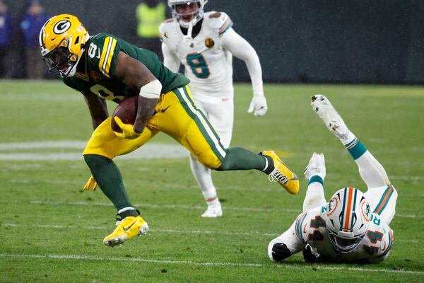 Green Bay Packers running back Josh Jacobs (8) breaks a tackle by Miami Dolphins linebacker Chop Robinson (44) during the second half of an NFL football game Thursday, Nov. 28, 2024, in Green Bay, Wis. (AP Photo/Mike Roemer)