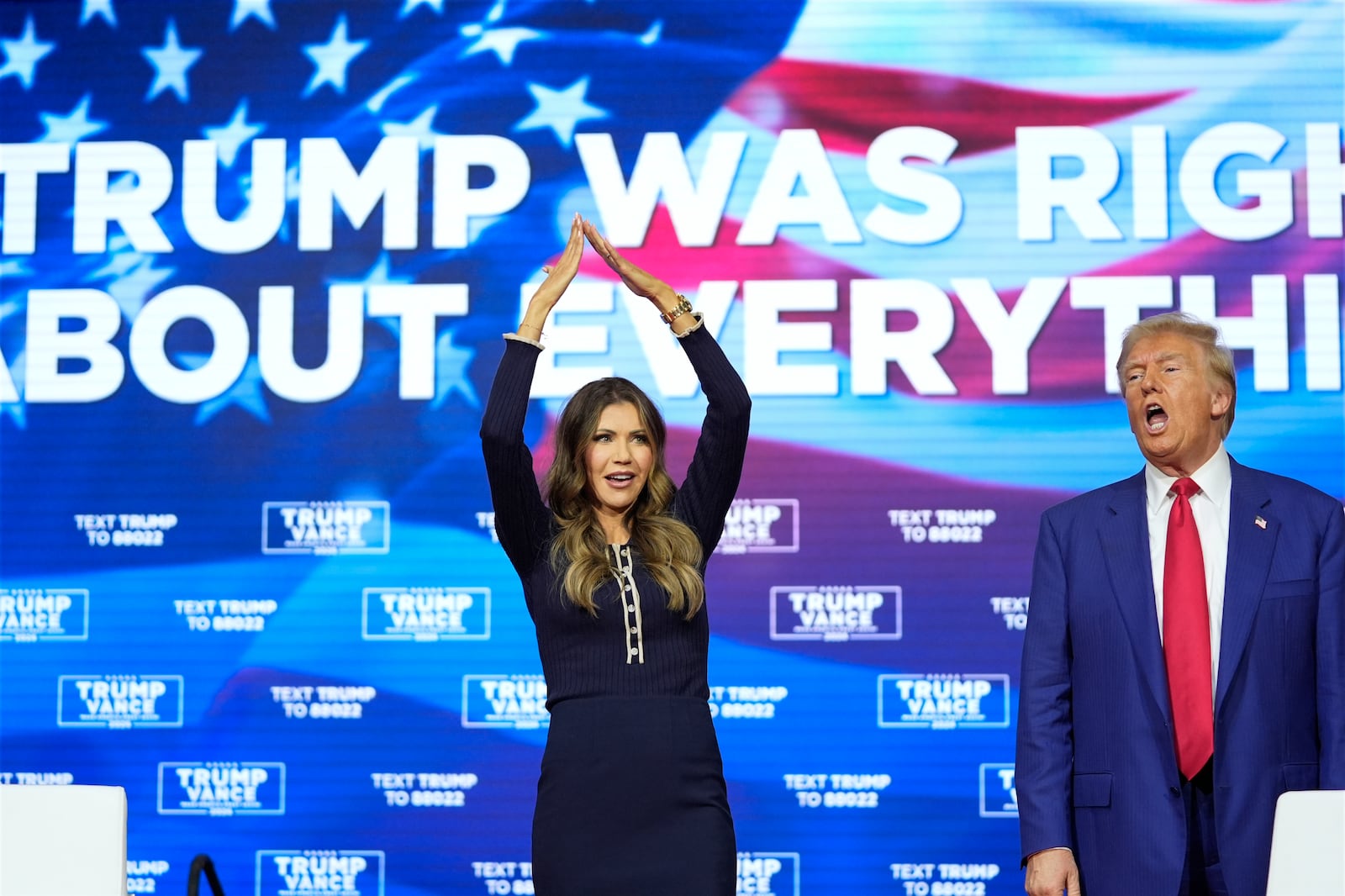 Republican presidential nominee former President Donald Trump watches as South Dakota Gov. Kristi Noem dances to the song "Y.M.C.A." at a campaign town hall at the Greater Philadelphia Expo Center & Fairgrounds, Monday, Oct. 14, 2024, in Oaks, Pa. (AP Photo/Alex Brandon)