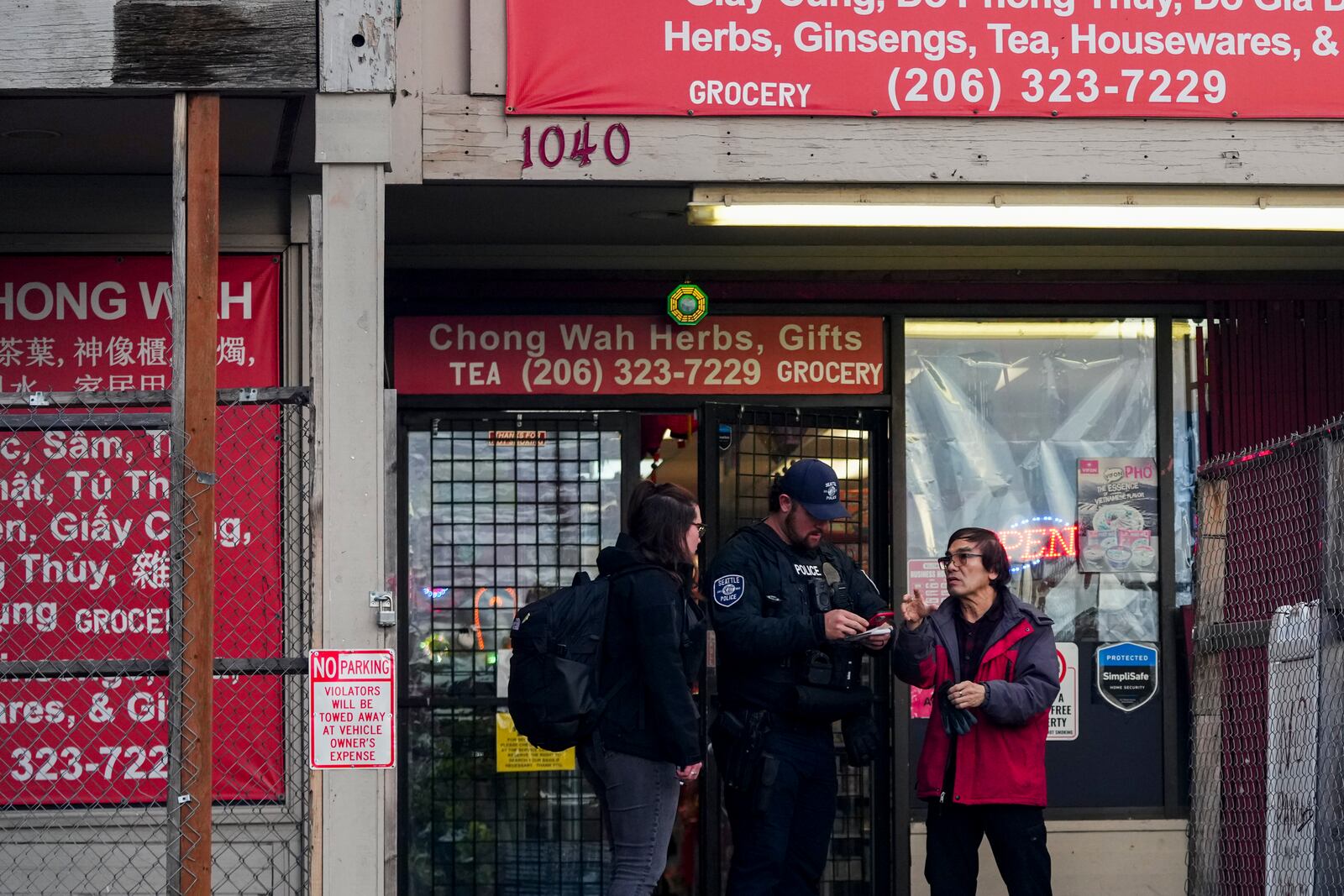 Police officers take a statement from a nearby business owner after multiple people were stabbed Friday, Nov. 8, 2024, in the Chinatown-International District in Seattle. (AP Photo/Lindsey Wasson)