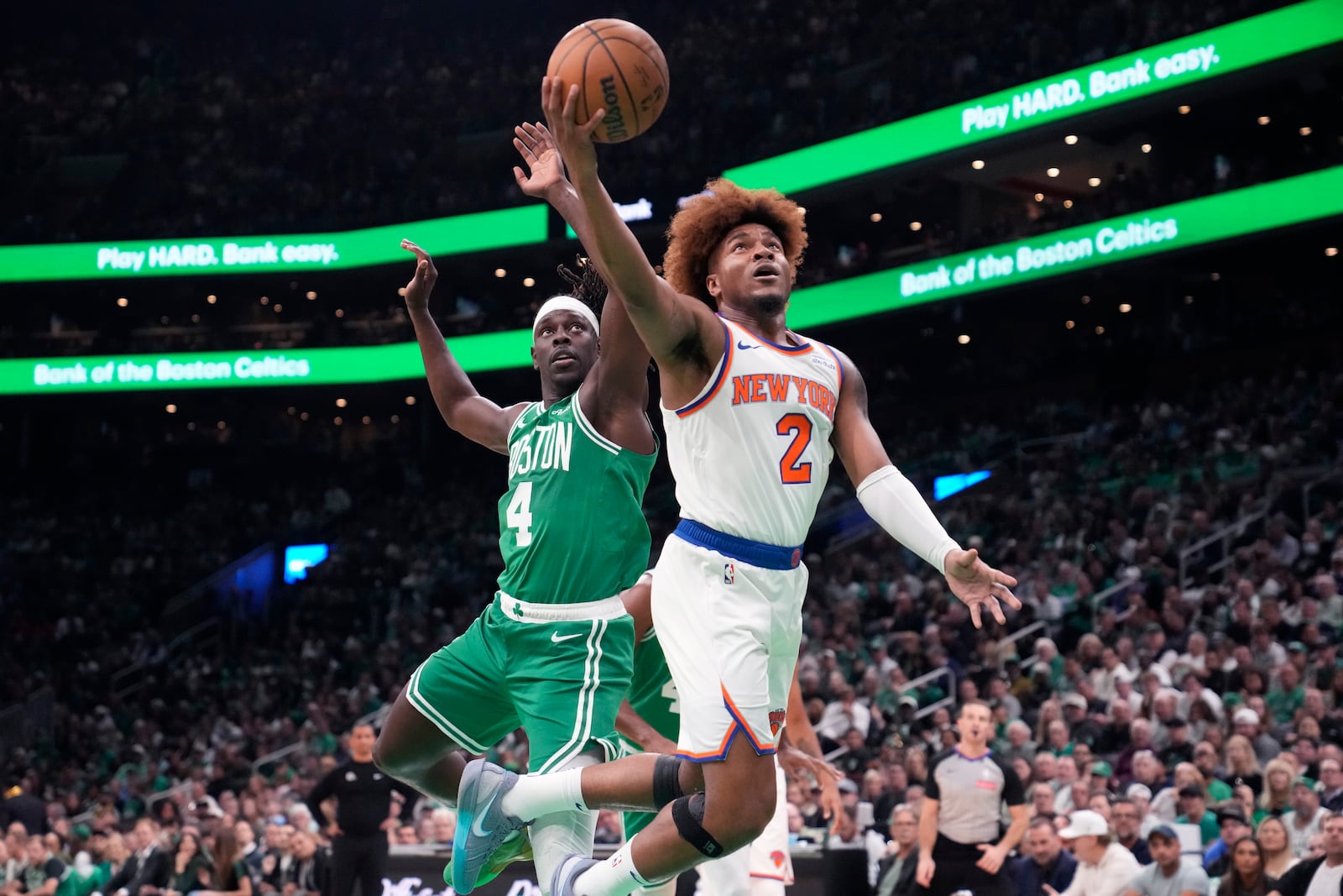 New York Knicks guard Miles McBride (2) drives to the basket past Boston Celtics guard Jrue Holiday (4) during the first half of an NBA basketball game, Tuesday, Oct. 22, 2024, in Boston. (AP Photo/Charles Krupa)