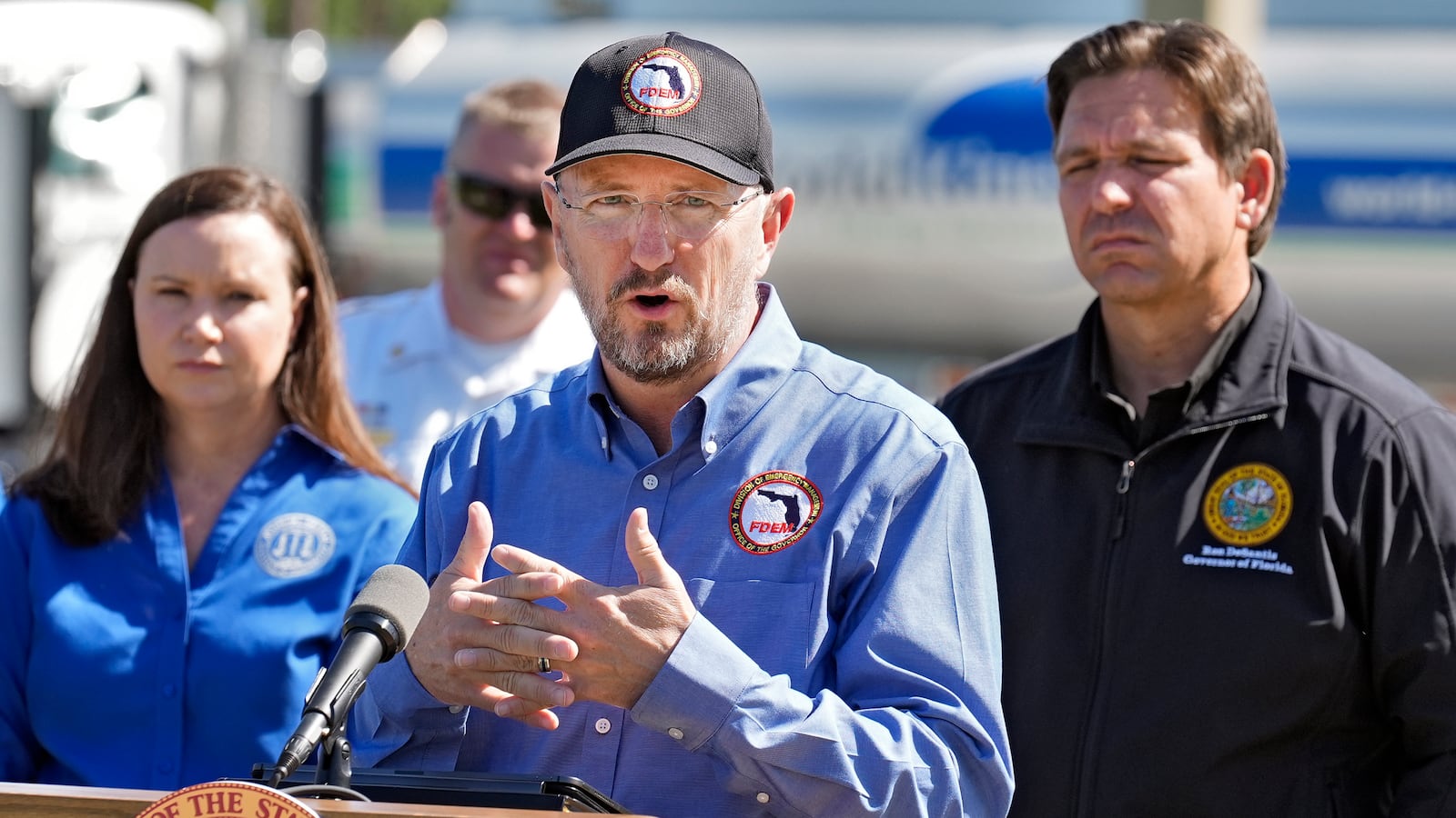 Kevin Guthrie, Florida Division of Emergency Management, speaks during a news conference at a newly opened fuel depot Saturday, Oct. 12, 2024, in Plant, Fla. Looking on are Florida Attorney General Ashley Moody, left, and Gov. Ron DeSantis, right. (AP Photo/Chris O'Meara)