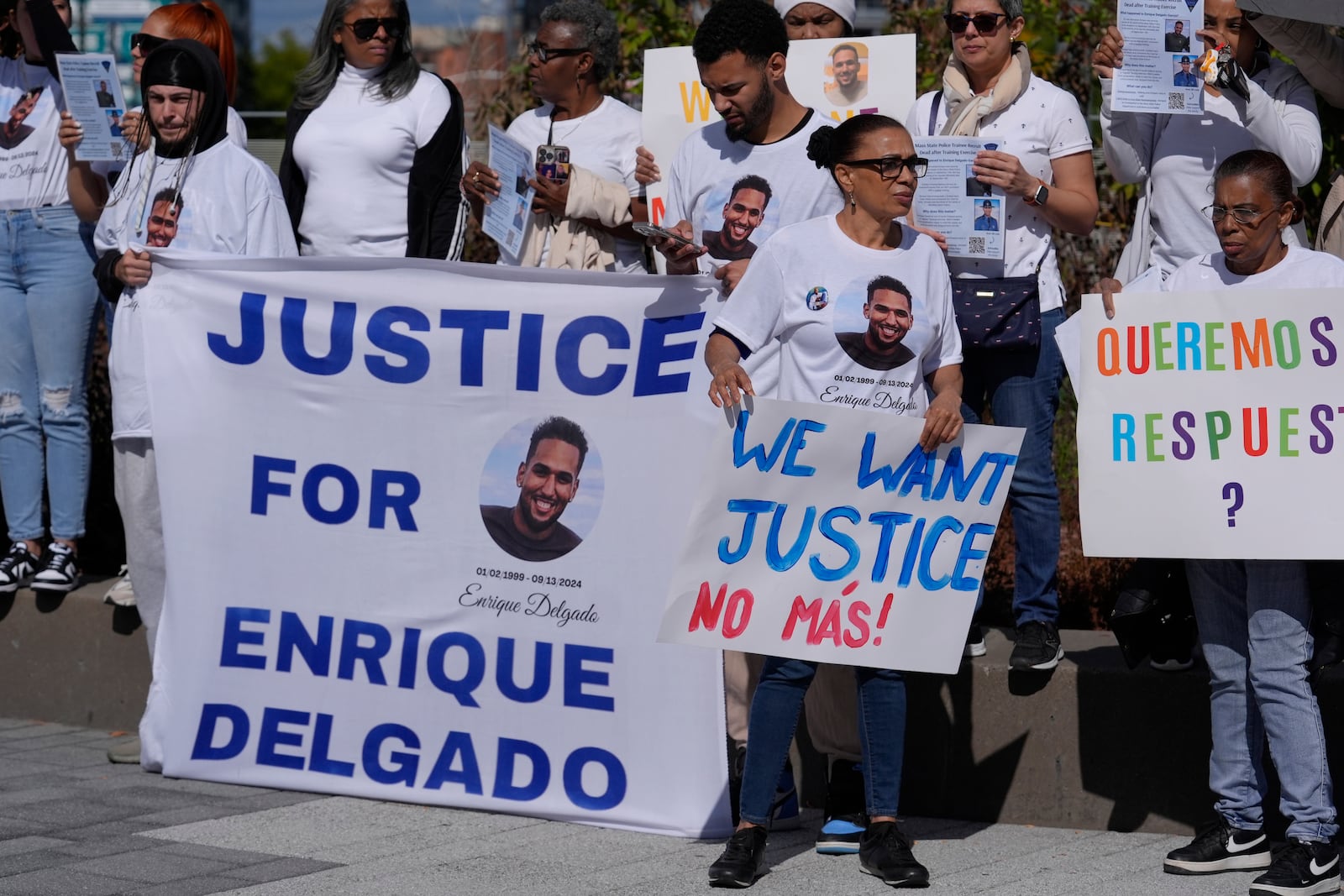 People display signs with with a likeness of Massachusetts State Police recruit Enrique Delgado-Garcia, who died following a State Police Academy training exercise, at a protest outside the State Police Academy graduation ceremony, Wednesday, Oct. 9, 2024, at the DCU Center, in Worcester, Mass. (AP Photo/Steven Senne)