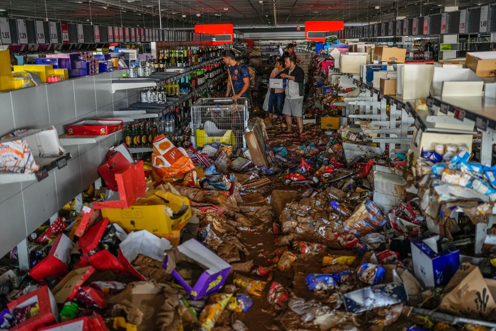 People pick up goods in a supermarket affected by the floods in Valencia, Spain, Thursday, Oct. 31, 2024. (AP Photo/Manu Fernandez)