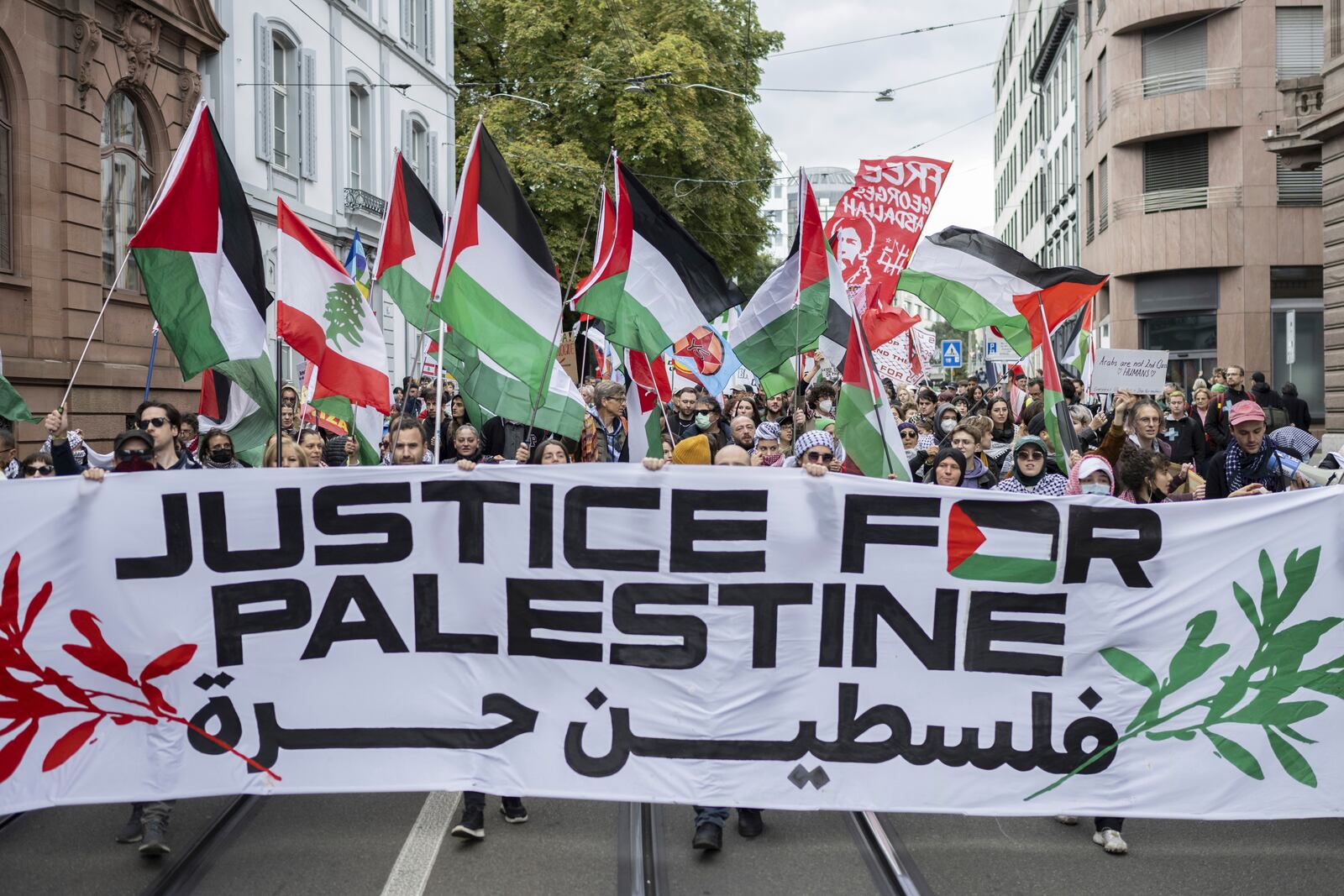 Protesters hold placards and Palestinian flags during a rally in support of the Palestinian people, in Basel, Switzerland, Saturday Oct. 5, 2024. (Ennio Leanza/Keystone via AP)