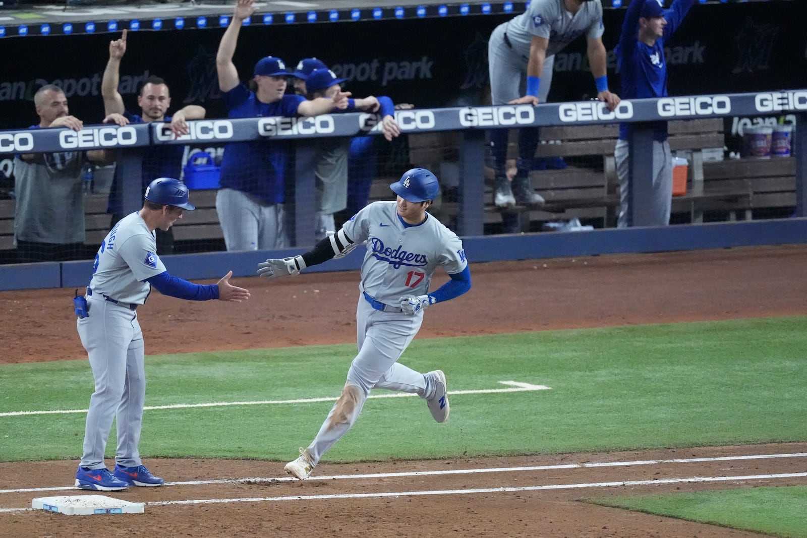 Los Angeles Dodgers first base coach Clayton McCullough, left, congratulates Shohei Ohtani (17) after Ohtani hit a home run scoring Andy Pages, during the sixth inning of a baseball game against the Miami Marlins, Thursday, Sept. 19, 2024, in Miami. (AP Photo/Wilfredo Lee)