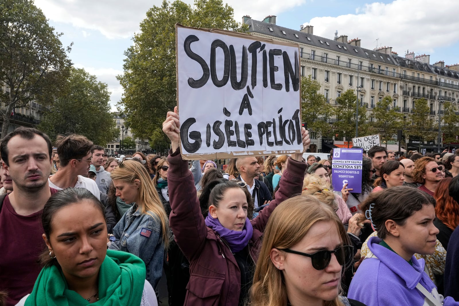 People take part in a gathering in support of 71-year-old Gisele Pelicot who was allegedly drugged by her ex-husband and raped by dozens of men while unconscious, Saturday, Sept. 14, 2024 in Paris. Placard reads, "support for Gisle Pelicot." (AP Photo/Michel Euler)