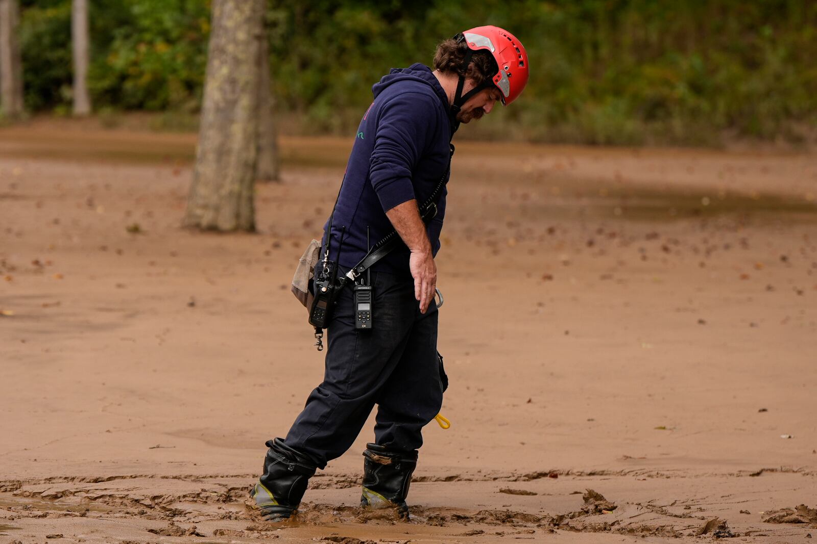 A fireman walks through mud as they search for victims of flash flooding in the aftermath of Hurricane Helene, Tuesday, Oct. 1, 2024, in Swannanoa, N.C. (AP Photo/Mike Stewart)