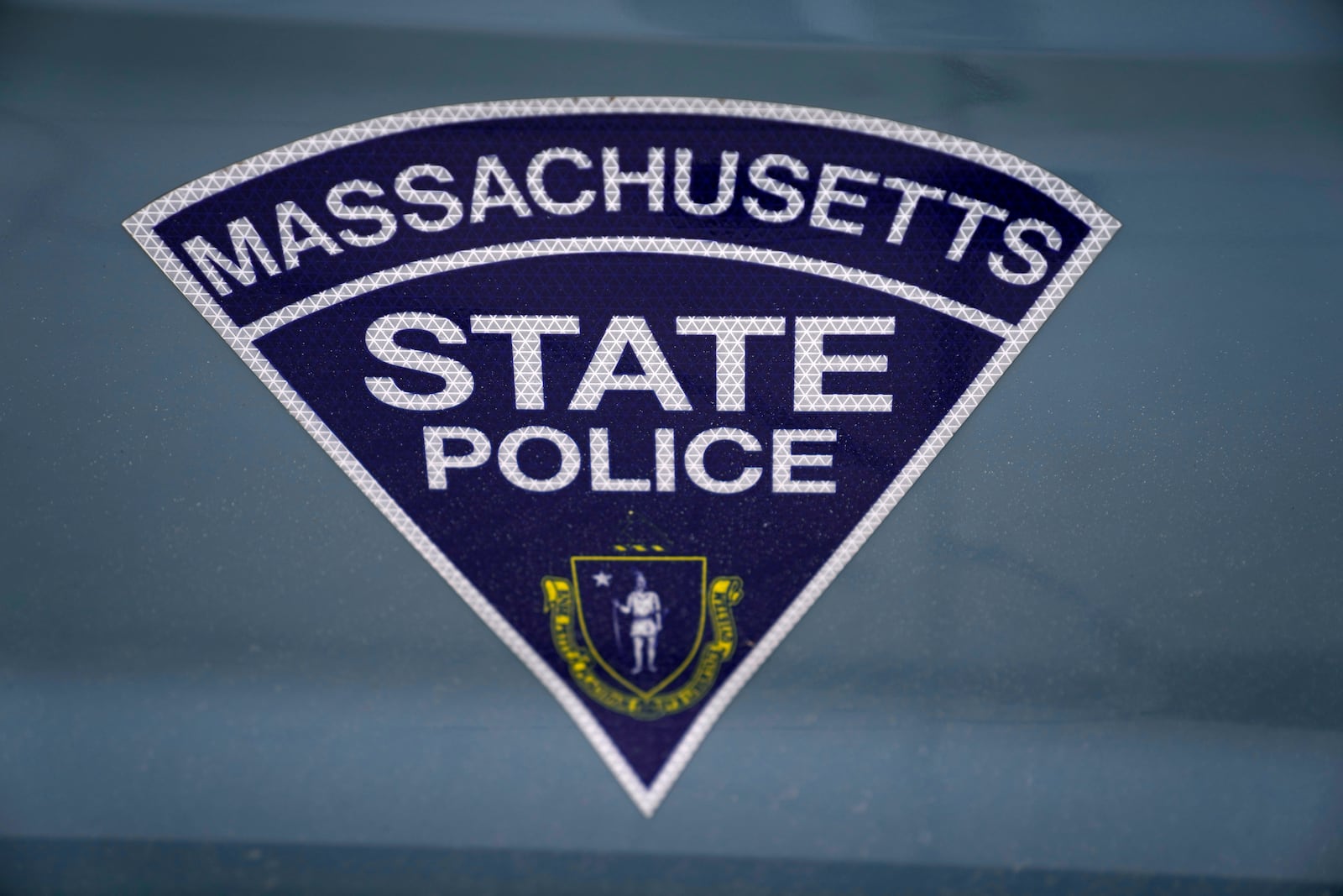 FILE - The seal of the Commonwealth of Massachusetts is displayed on a Massachusetts State Police cruiser parked outside the Statehouse, March 3, 2023, in Boston. (AP Photo/Charles Krupa, File)