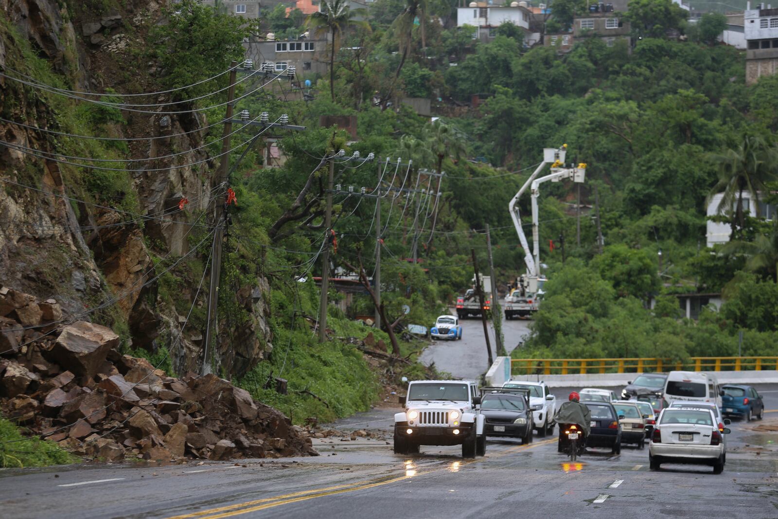 Residents drive past power lines damaged during the passing of Hurricane John, in Acapulco, Mexico, Friday, Sept. 27, 2024. (AP Photo/Bernardino Hernandez)