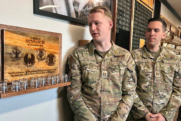 Osprey pilots Capt. Christian Eells, left, and Capt. Matthew Gulotta stand Oct. 8, 2024, at Cannon Air Force Base, N.M., beside a memorial to the Air Force Special Operations Command Osprey callsign "Gundam 22" that crashed off the coast of Japan in November 2023, killing all eight service members aboard. (AP Photo/Tara Copp)