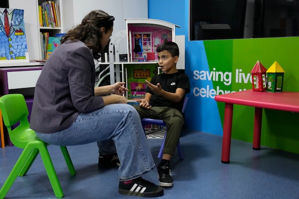 Mohammad Mousawi, 8, a displaced boy from the southern suburb of Beirut who suffers from leukaemia, attends with a volunteer who offers him a compassionate care and entertainment ahead of his weekly treatment at the Children's Cancer Center of Lebanon, in Beirut, Lebanon, Friday, Nov. 15, 2024. (AP Photo/Hussein Malla)