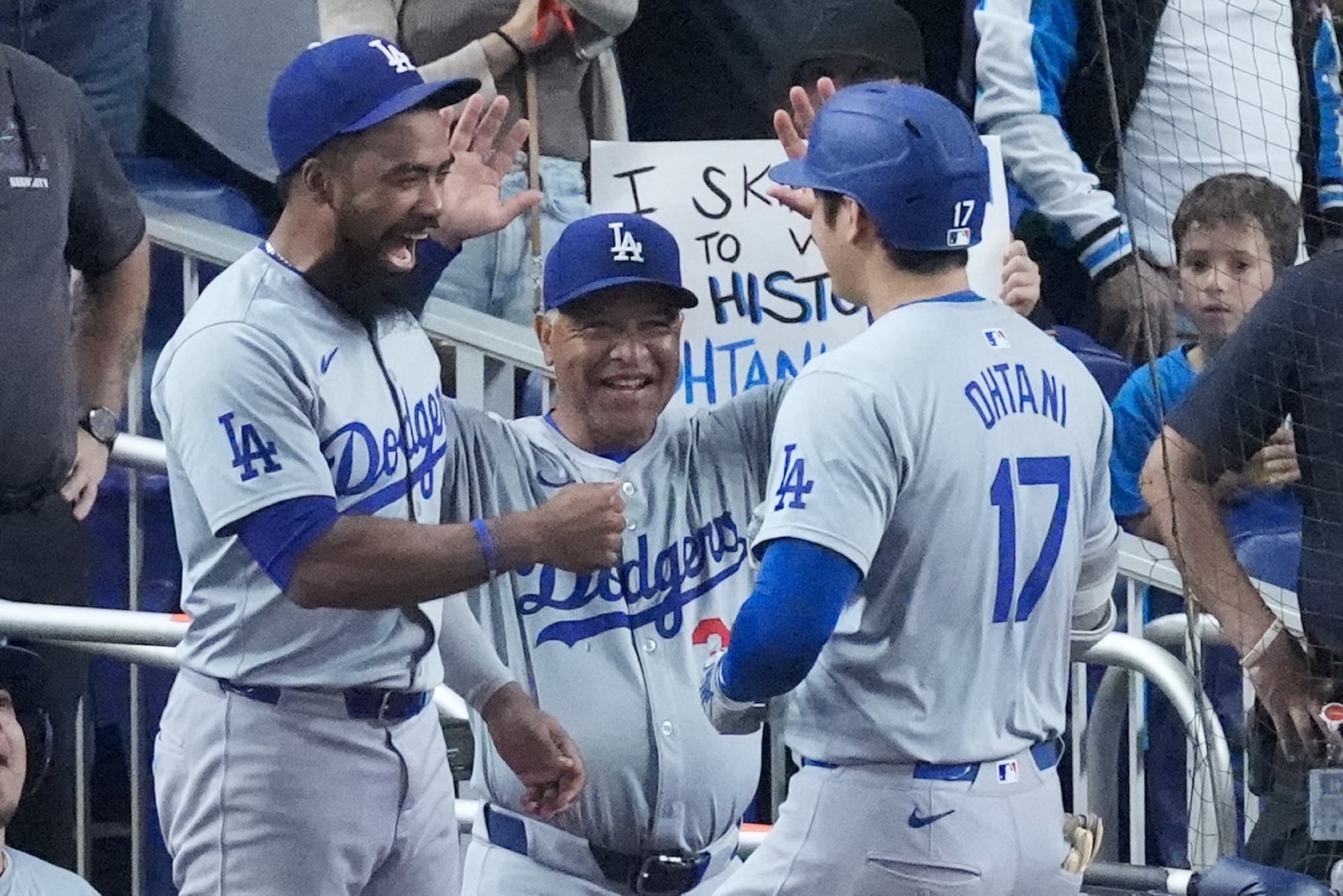 Los Angeles Dodgers' Teoscar Hernández, left, and manager Dave Roberts, center, congratulate Shohei Ohtani (17) after Ohtani hit a home run scoring Andy Pages during the sixth inning of a baseball game against the Miami Marlins, Thursday, Sept. 19, 2024, in Miami. (AP Photo/Wilfredo Lee)