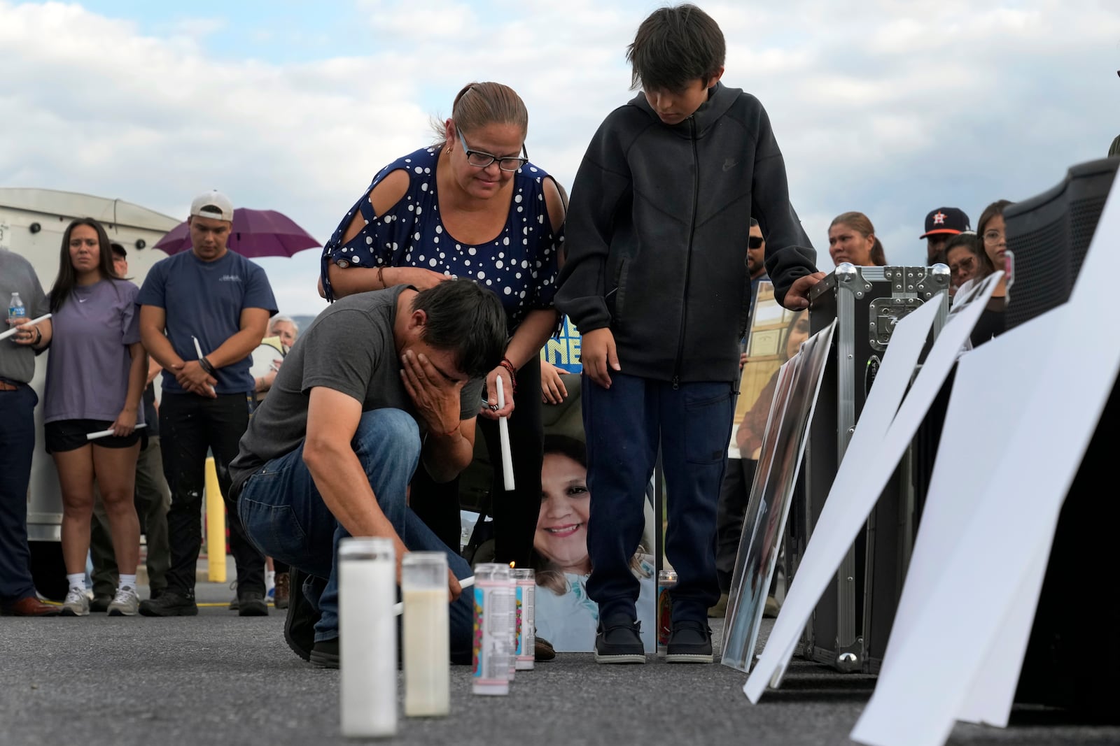 Daniel Delgado kneels in front of a photo of his wife, Monica Hernandez, who died at Impact Plastics during flooding caused by Hurricane Helene, while being comforted by his sister-in-law, Guadalupe Hernandez-Corona, during a vigil for victims of the tragedy in Erwin, Tenn., on Thursday, Oct. 3, 2024. (AP Photo/Jeff Roberson)