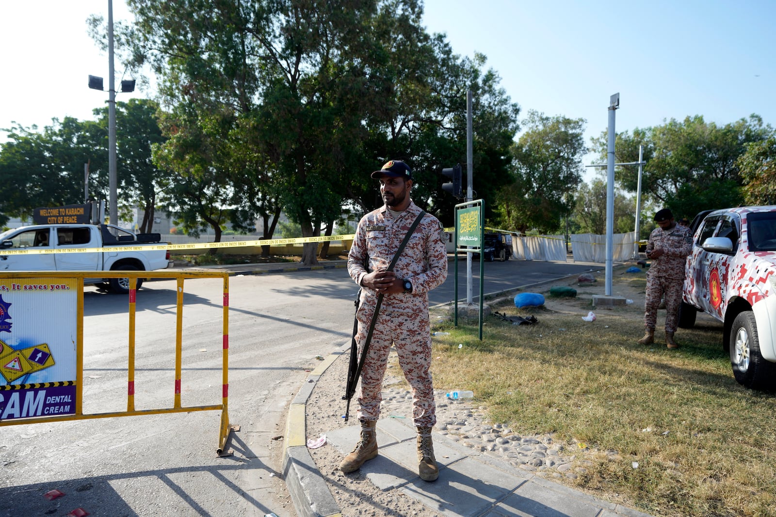 Security officials stand guard next to the site of an explosion that caused injures and destroyed vehicles outside the Karachi airport, Pakistan, Monday, Oct. 7, 2024. Pakistani Baloch separatists claim deadly bomb attack that killed 2 Chinese near Karachi airport. (AP Photo/Fareed Khan)