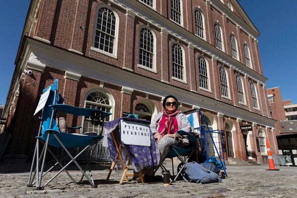 FILE - A fortune teller going by the name of Andrea waits for customers in front of Faneuil Hall in Boston, on a plaza that is usually busy with tourists, March, 14, 2020. (AP Photo/Michael Dwyer, File)