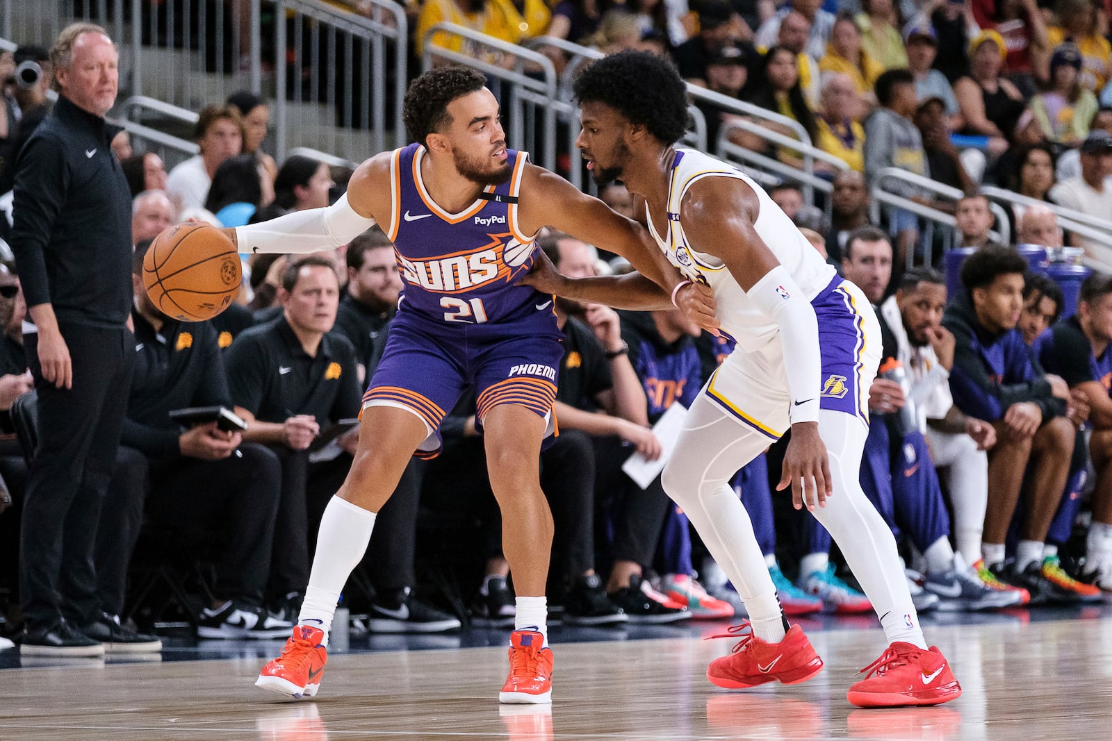 Phoenix Suns guard Tyus Jones (21) dribbles under pressure from Los Angeles Lakers guard Bronny James (9) during the first half of a preseason NBA basketball game Sunday, Oct. 6, 2024, in Palm Desert, Calif. (AP Photo/William Liang)