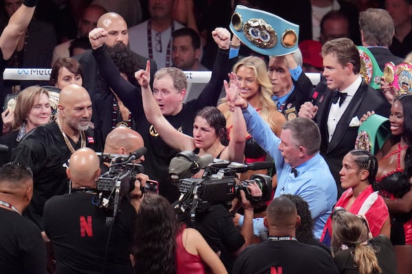 Katie Taylor, center, celebrates after defeating Amanda Serrano during their undisputed super lightweight title bout, Friday, Nov. 15, 2024, in Arlington, Texas. (AP Photo/Julio Cortez)