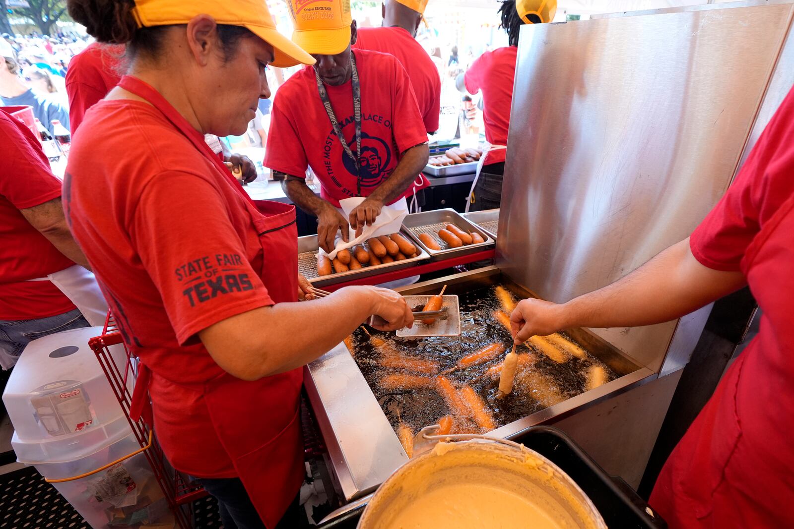 Carmen Zapata, left, helps prepare dozens of Fletchers Corny dogs at their booth at the State Fair of Texas in Dallas, Friday, Sept. 27, 2024. (AP Photo/Tony Gutierrez)