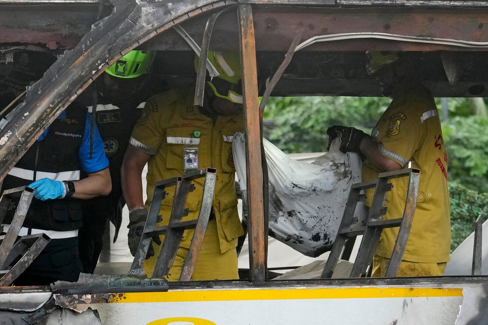 Rescuers carry the body of a victim of a bus that caught fire, carrying young students with their teachers, in suburban Bangkok, Tuesday, Oct. 1, 2024. (AP Photo/Sakchai Lalit)