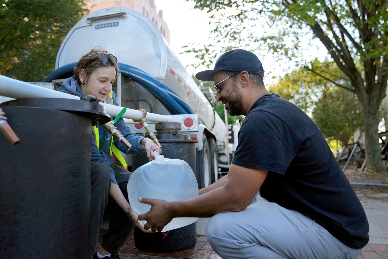 Reginald Klemz, right, fills a container of fresh water from a tanker with the help of volunteer Julie Koenke in the aftermath of Hurricane Helene Wednesday, Oct. 2, 2024, in Asheville, N.C. (AP Photo/Jeff Roberson)