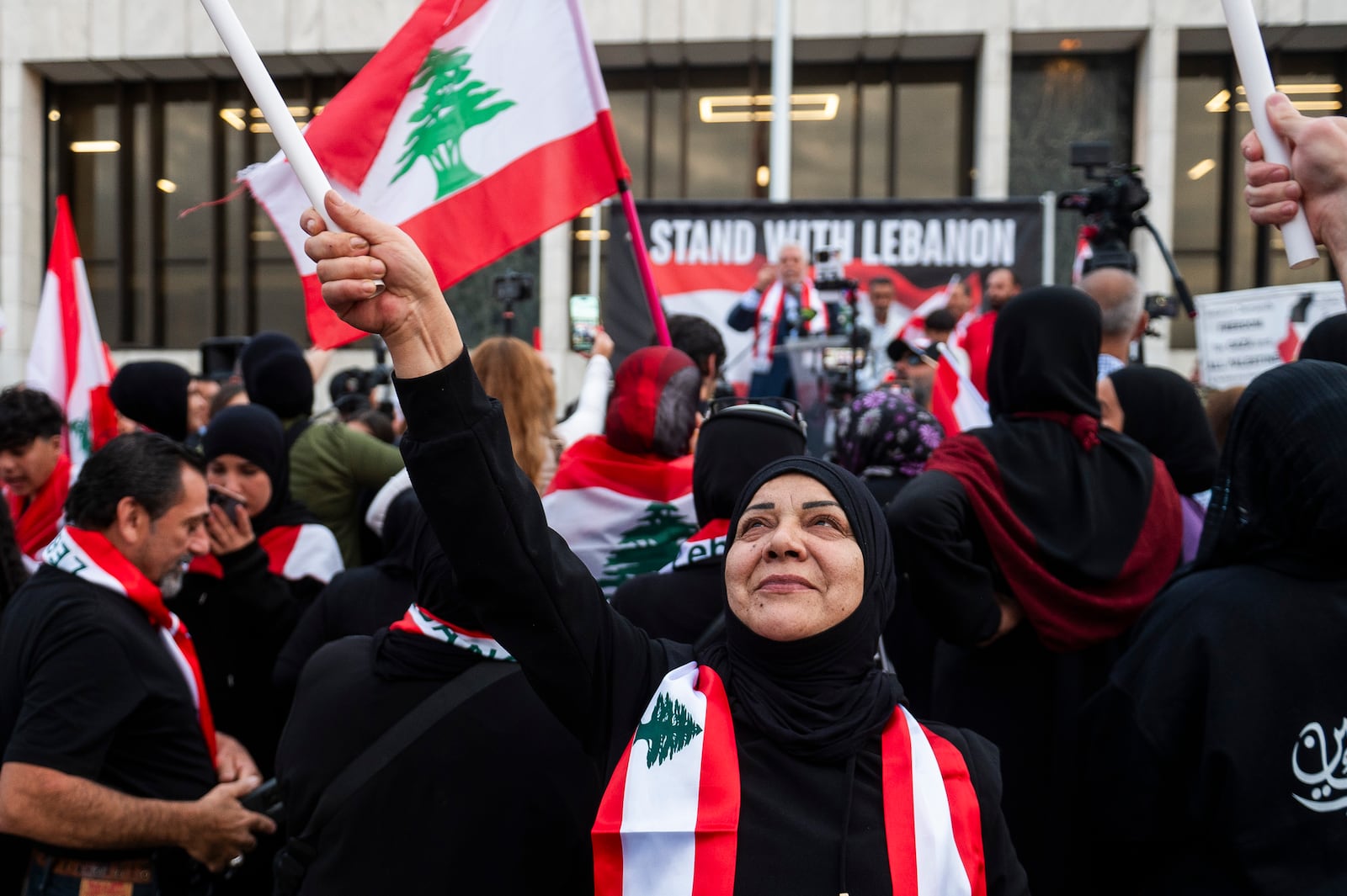 Najah Harb of Dearborn waves a Lebanese flag above her head as hundreds gather for a rally in support of Lebanon in light of recent Israeli strikes that killed hundreds, on Wednesday, Sept. 25, 2024 in front of the Henry Ford Centennial Library in Dearborn, Mich. (Katy Kildee/Detroit News via AP)