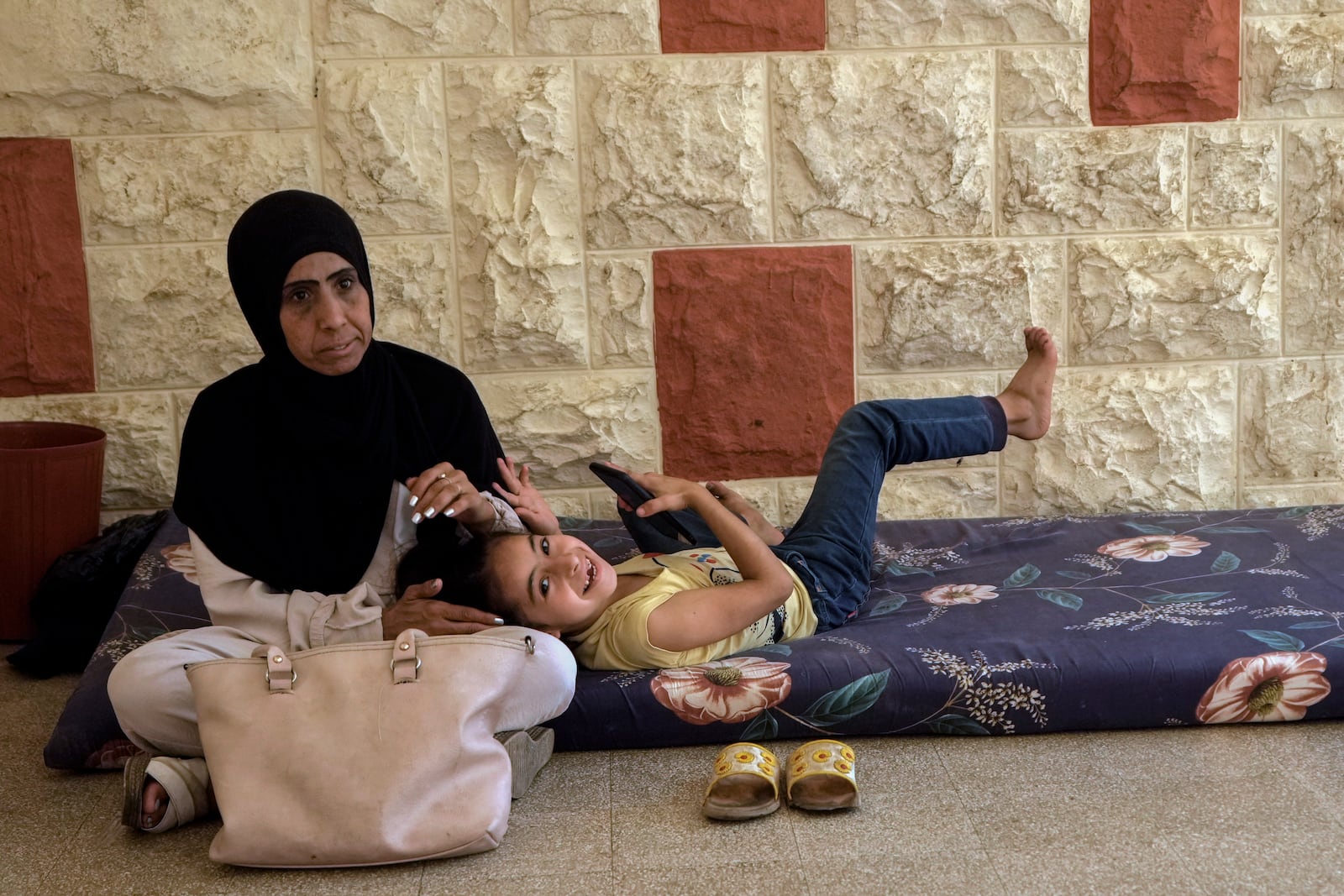 A displaced woman sits with her daughter at a vocational training center run by the U.N. agency for Palestinian refugees, or UNRWA, in the southern town of Sebline, south of Beirut, Lebanon, Friday, Oct. 4, 2024, after fleeing the Israeli airstrikes in the south. (AP Photo/Bilal Hussein)