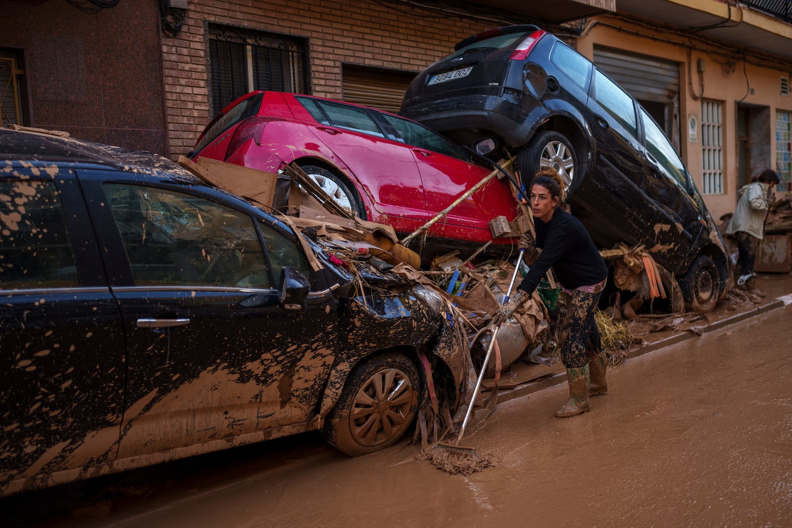 A woman cleans the street of mud in an area affected by floods in Sedavi, Spain, on Friday, Nov. 1, 2024. (AP Photo/Manu Fernandez)