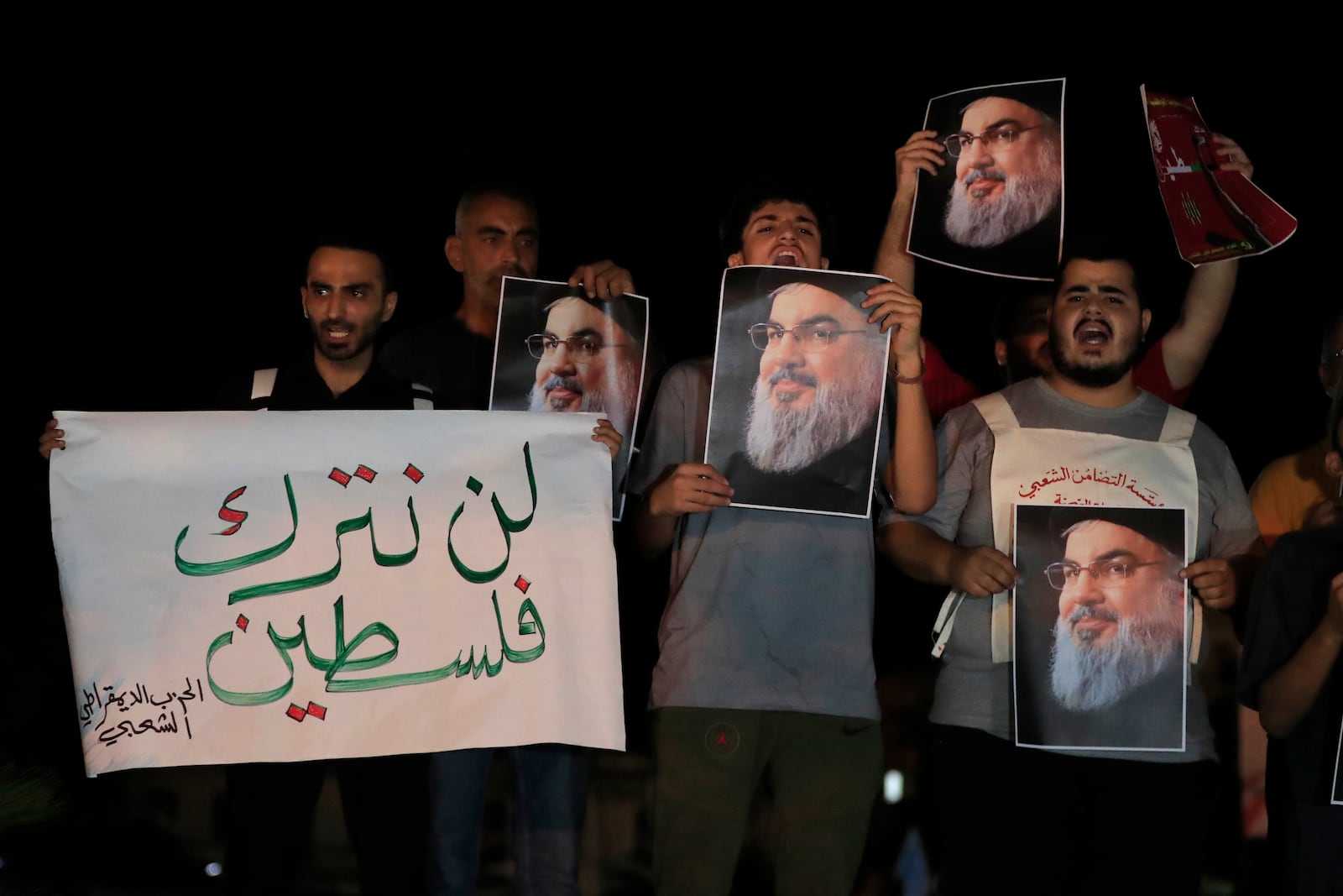 Lebanese and Palestinian men hold portraits of Hezbollah leader Sayyed Hassan Nasrallah and an Arabic placard that reads:"Will not keep Palestine," as they shout slogans during a protest in the southern port city of Sidon, Lebanon, Saturday, Sept. 28, 2024. (AP Photo/Hussein Malla)