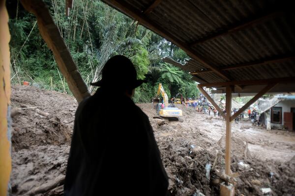 A villager looks on as rescuers use a heavy machinery to search for victims of a landslide that killed a number of people and left some others missing in Karo, North Sumatra, Indonesia, Monday, Nov. 25, 2024. (AP Photo/Binsar Bakkara)