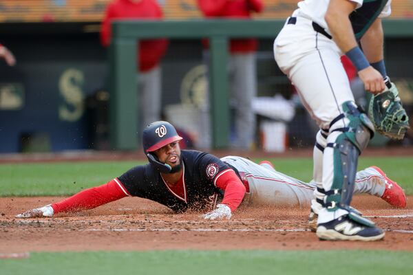 Washington Nationals' Luis Garcia Jr. slides home to score past Seattle Mariners catcher Cal Raleigh off a single hit by Robert Hassell III during the fourth inning of a baseball game Wednesday, May 28, 2025, in Seattle. (AP Photo/Ryan Sun)
