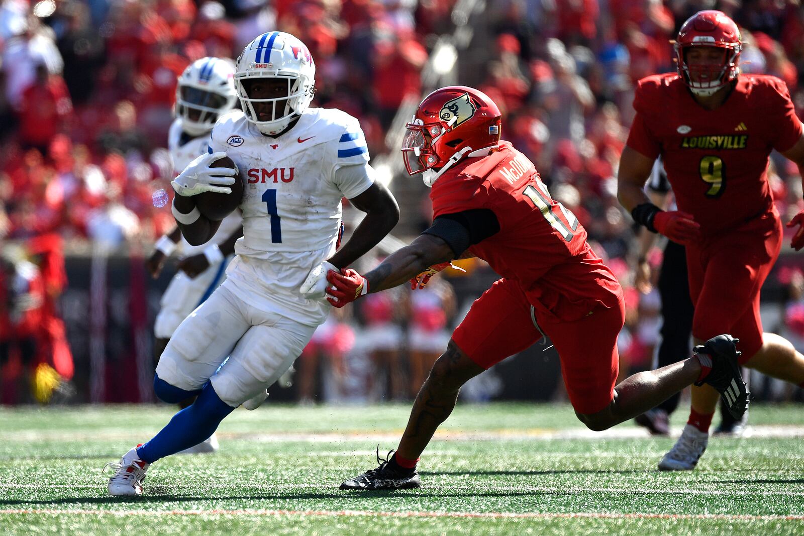 SMU running back Brashard Smith (1) runs from the grasp of Louisville defensive back Tamarion McDonald (12) during the second half of an NCAA college football game in Louisville, Ky., Saturday, Oct. 5, 2024. (AP Photo/Timothy D. Easley)