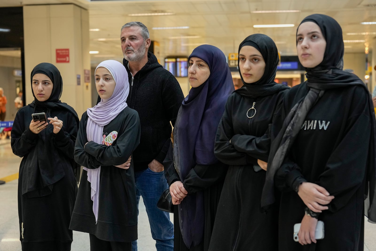 Lebanese citizen Ali Zeineddine, third from left, waits with family for his brother arriving from Lebanon at Sao Paulo International airport, after an Israeli air strike killed various members of their family, Thursday, Oct. 3, 2024. (AP Photo/Andre Penner)